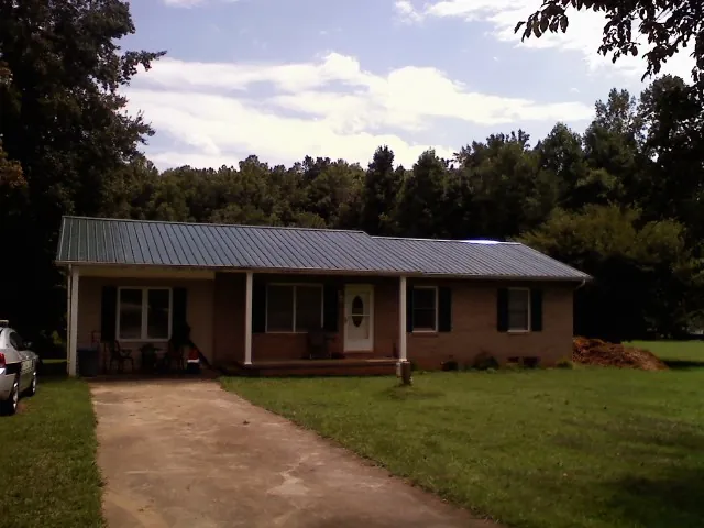 Dark green metal roof on a brick ranch with a covered porch in Connellsville