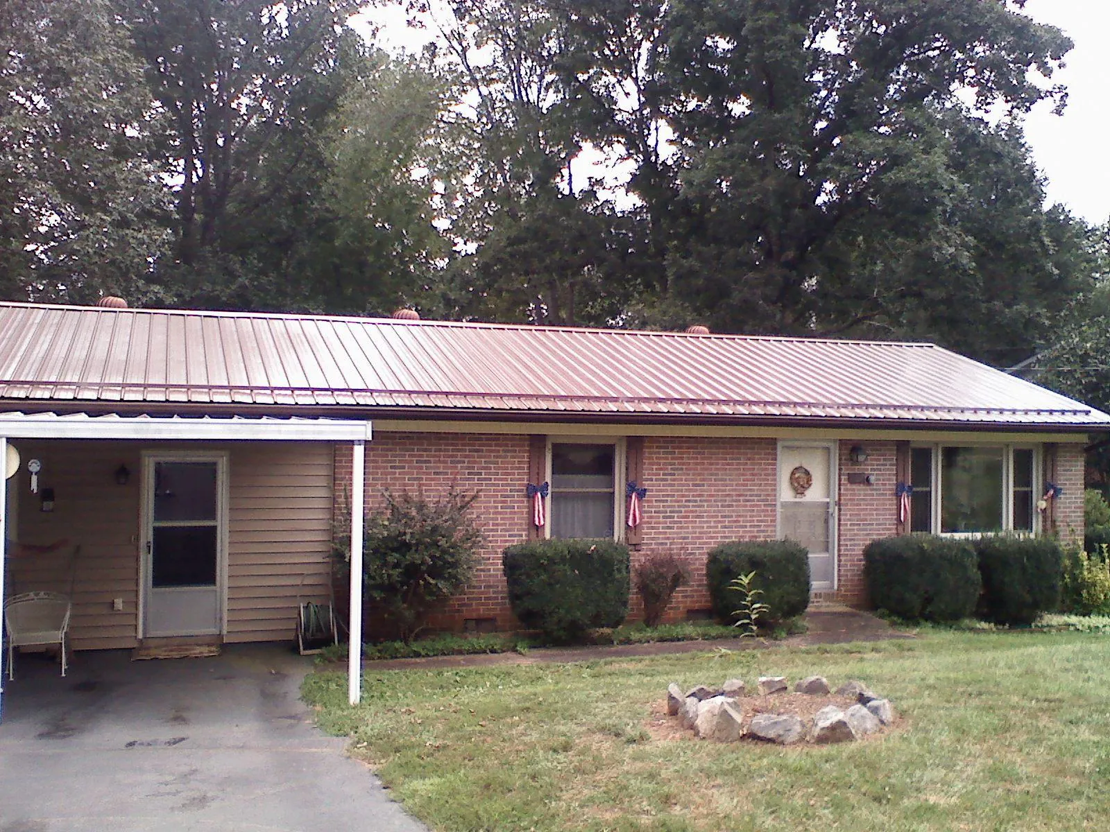 Bronze metal roof and carport on a brick ranch home — Roof Repair work by our crew in Connellsville