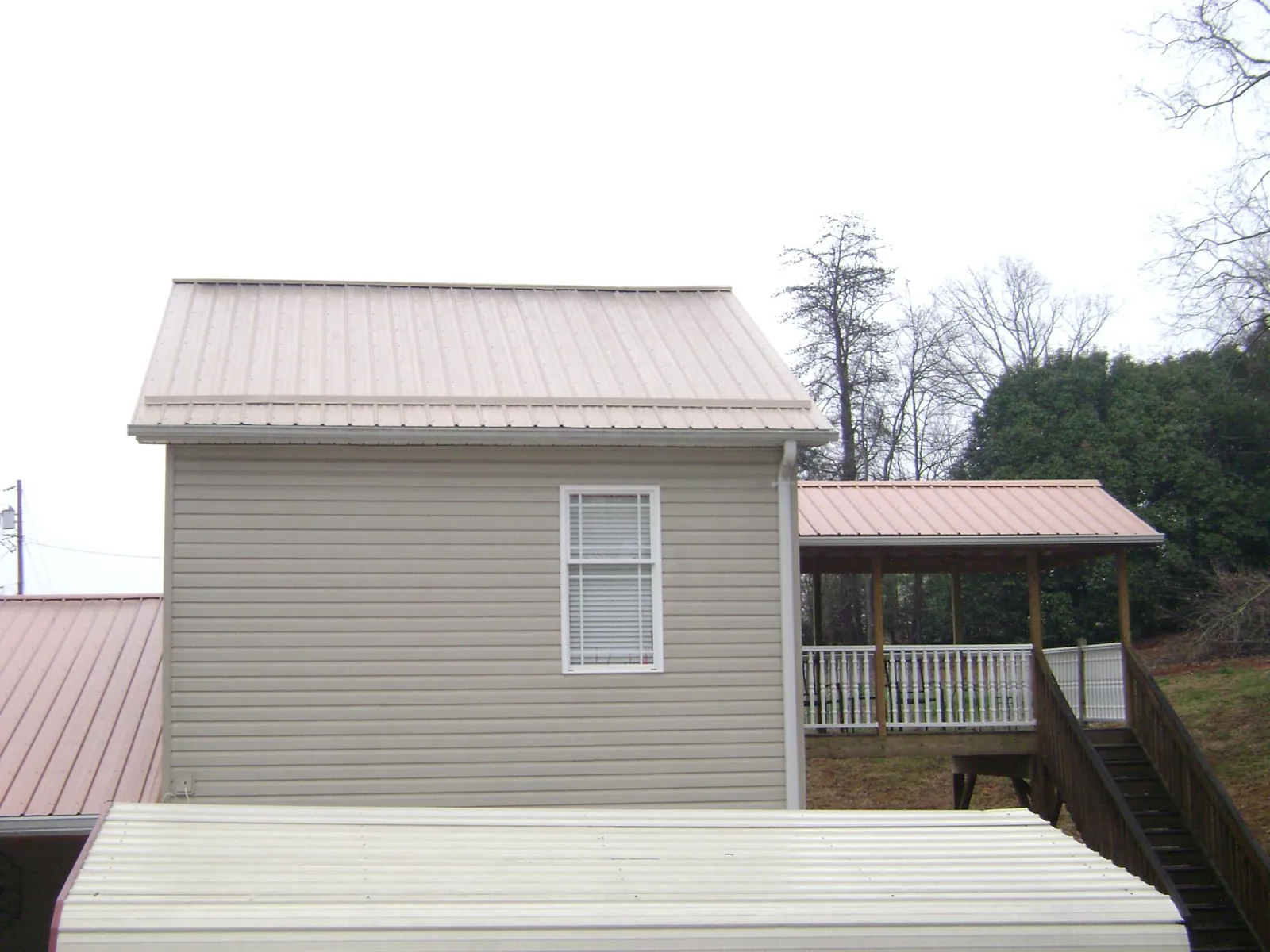 Tan metal roofs on a two story addition and attached porch, from a Roof Replacement job in Connellsville