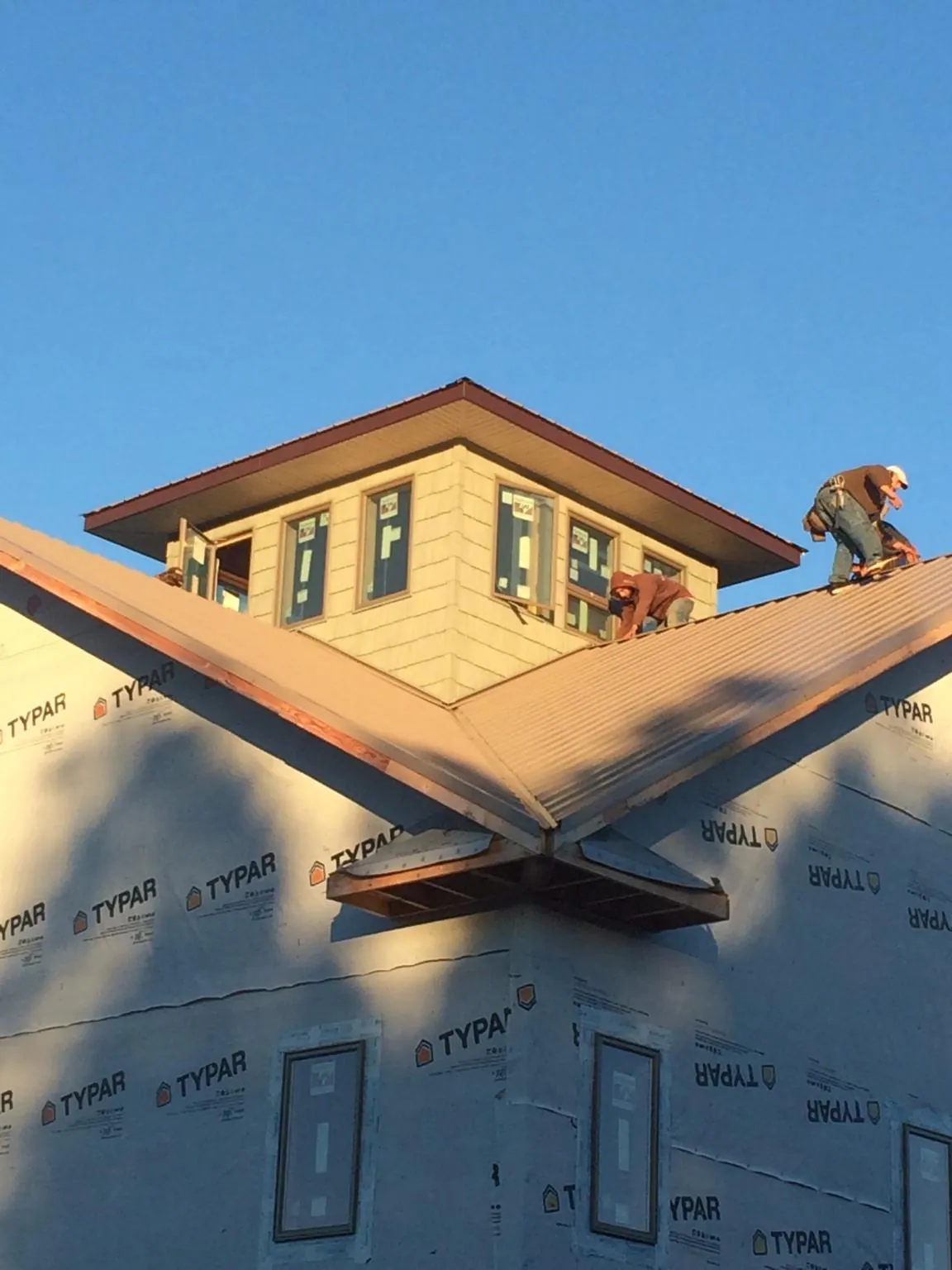 Roofers working around a rooftop cupola on a new metal roof at sunset — Roof Waterproofing in Connellsville by Roofing Brothers